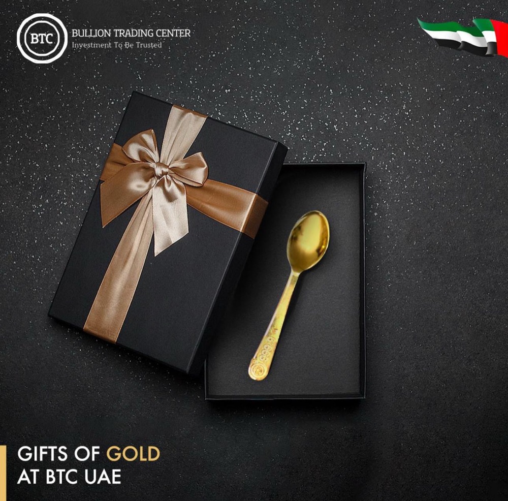 A gold baby spoon in an open black gift box with a satin bow